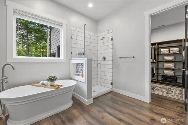 Soaking tub with pull out wand and custom niche, Separate oversized walk in shower features subway tile and soap dispensers.