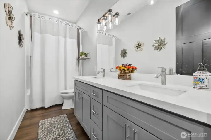 Main bathroom offers tub with shower niche cubby, 2 sinks with quartz countertops.