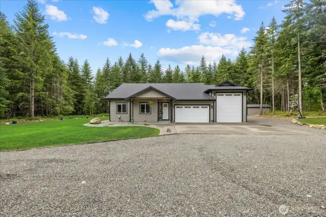 Front view of home.  Low maintenance yard with custom curbing -  the rest of the 5 acres are forested for privacy.   Well house with storage pictured to the right out back.  Aggregate driveway and 8x16' covered wood storage.
