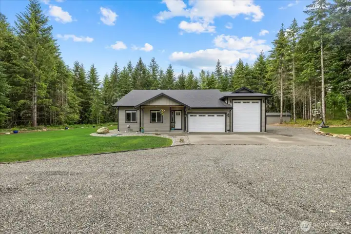 Front view of home.  Low maintenance yard with custom curbing -  the rest of the 5 acres are forested for privacy.   Well house with storage pictured to the right out back.  Aggregate driveway and 8x16' covered wood storage.