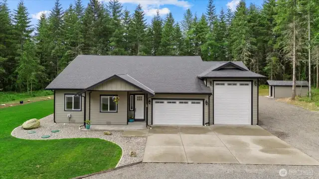 Home sweet home.  Aggregate driveway, well house with storage seen to the right and gravel walkways throughout.