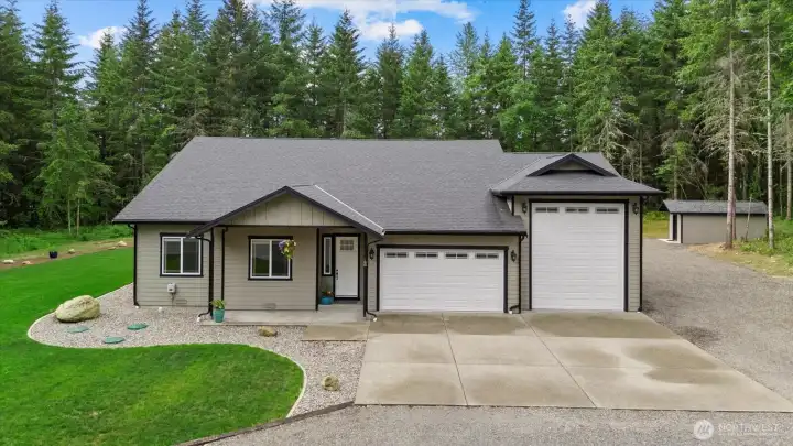 Home sweet home.  Aggregate driveway, well house with storage seen to the right and gravel walkways throughout.