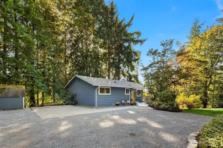 Front of house, large parking area and storage shed.