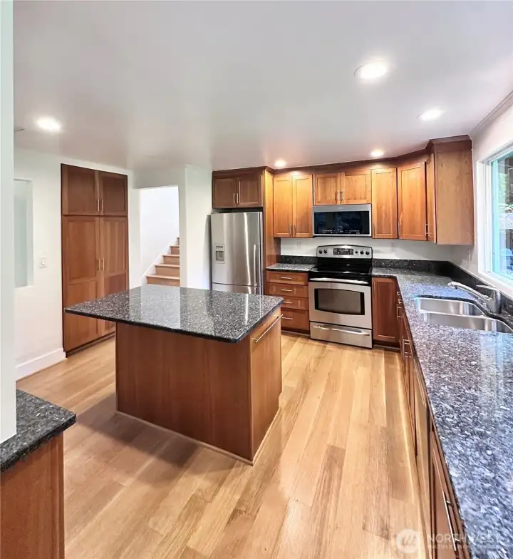 The open-concept living area boasts a statement fireplace and a chef’s dream kitchen with granite countertops, SS appliances, and an island with even more storage.