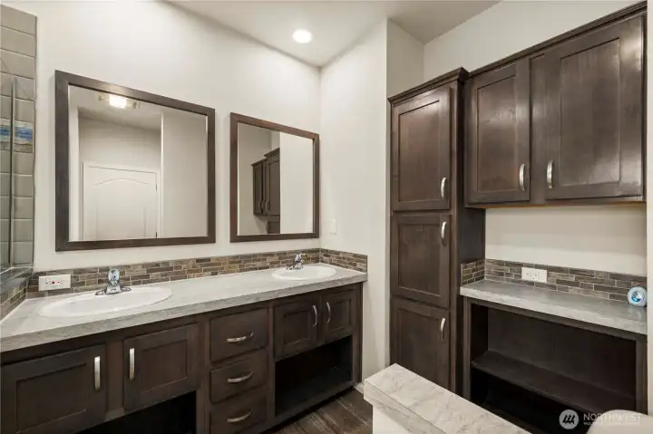 Primary bathroom features a long dual-sink vanity, generous cabinetry, additional storage space and a functional layout for daily routines.