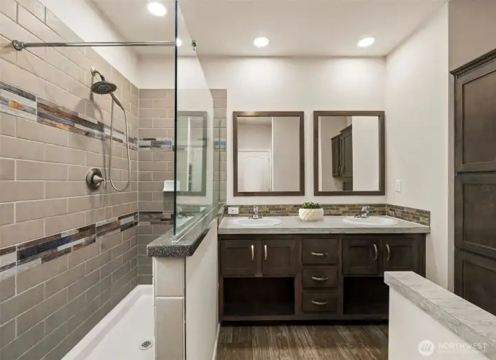 Large walk-in shower with tile surround and glass enclosure creates a bright, spa-like feel.  (photo virtually staged w/plant)