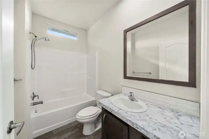 Guest bathroom features a tub/shower combination, modern vanity, and clean, bright finishes.
