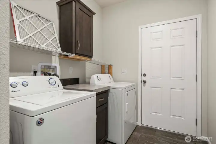 Dedicated laundry area includes washer and dryer with added storage for everyday convenience.