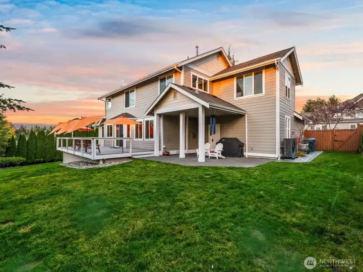 Back exterior of Horizon West home for sale in North Gig Harbor showcasing a fenced backyard, expansive Trex deck, and covered patio—perfect for year-round Pacific Northwest living near Downtown Gig Harbor and Hwy 16.