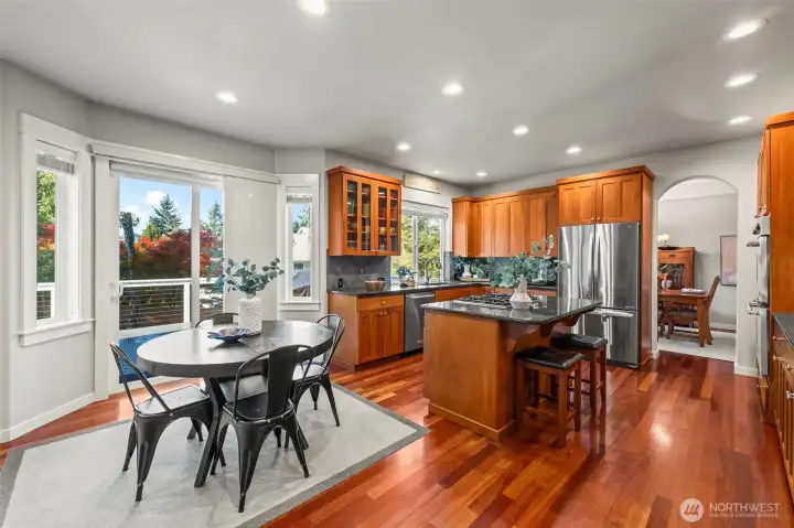 Bright kitchen and informal dining area in Horizon West home for sale in North Gig Harbor with granite counters, stainless steel appliances, and sliding doors leading to a spacious Trex deck and fenced backyard for easy indoor-outdoor living.