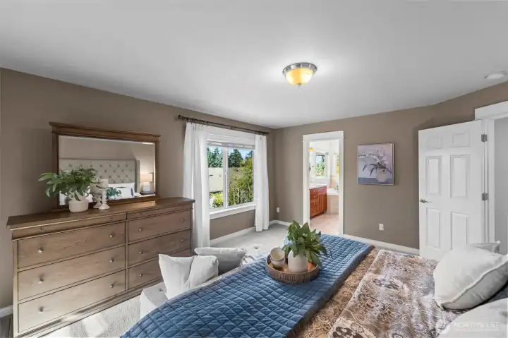 Primary bedroom in Horizon West home for sale in North Gig Harbor featuring peek-a-boo views of Henderson Bay and the Olympic Mountains, with a view toward the ensuite spa-style bath—combining comfort, scenery, and luxury living.