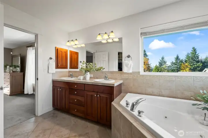 Primary ensuite bathroom in Horizon West home for sale in North Gig Harbor featuring dual vanities, a soaking tub with large picture windows, and elegant finishes—offering a spa-like retreat with natural light and comfort.