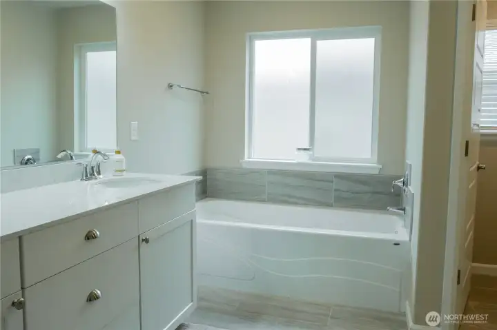 Primary bathroom suite with dual vanity sinks and tub