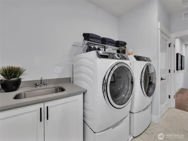 Convenient 2nd floor laundry room with utility sink and GE front load washer/dryer.