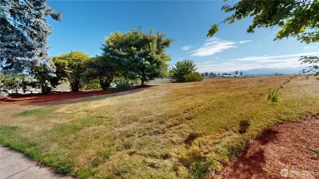 Picturesque outdoor setting with expansive open land, lush greenery, and breathtaking mountain views in the distance