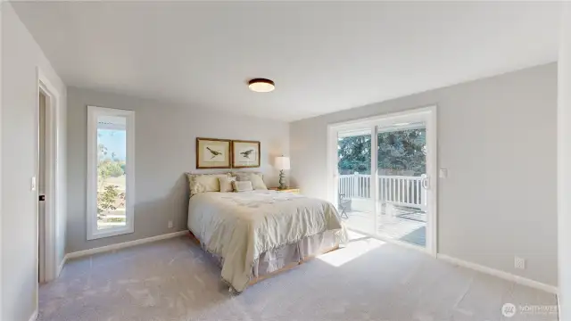 Bright and serene primary bedroom with large sliding glass door leads to a private deck