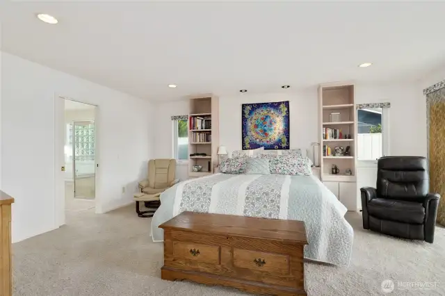 Serene primary bedroom retreat featuring a cozy fireplace, stunning water views, direct patio access, ensuite, walk-in closet, and a private office for work or exercising with electric open skylight.