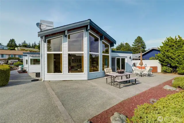 Stunning view from the back of the house, featuring large windows that frame the water and an expansive patio perfect for outdoor entertaining.