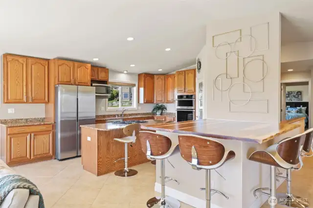 gourmet kitchen with custom raw-edge wood peninsula that seats 4 plus