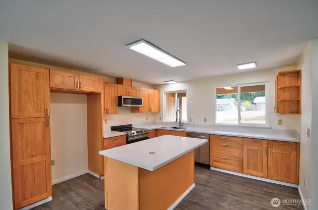 Kitchen features island with eating bar, quartz counters, under-mount single sink. Stainless steel stove, microwave and dishwasher.
