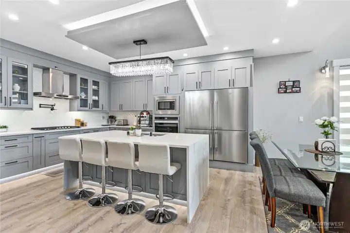 Elegant kitchen with stainless steel appliances, under cabinet led lighting & large island with seating area.