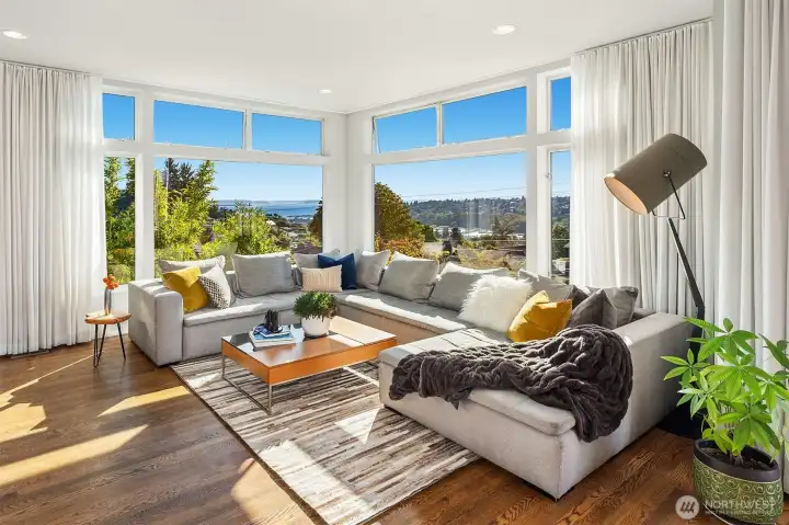 Sun drenched living room with stunning views of Elliot Bay, the sound and the Olympic Mountains.