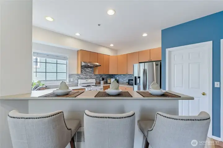 The kitchen features a bar that opens to the living area, creating a seamless flow that's ideal for entertaining guests or serving loved ones meals and snacks.