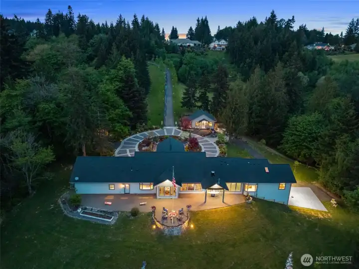 Twilight descends on this 12 acre in town private estate property. Subdivision is gated and this property also gated. Huge patio has multiple accesses. Enjoy the firepit or the covered outdoor kitchen. The lodge can be seen at the upper right of the circular driveway.