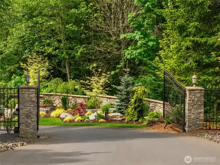The landscaped and gated entry. Road winds to the left and then to the right to reveal all that is hidden behind the  gate at this one of a kind property.