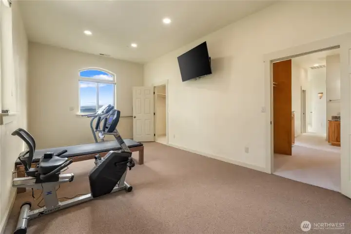 Workout/flex room with mounted TV. Doorway to the right leads to "His" dressing room.