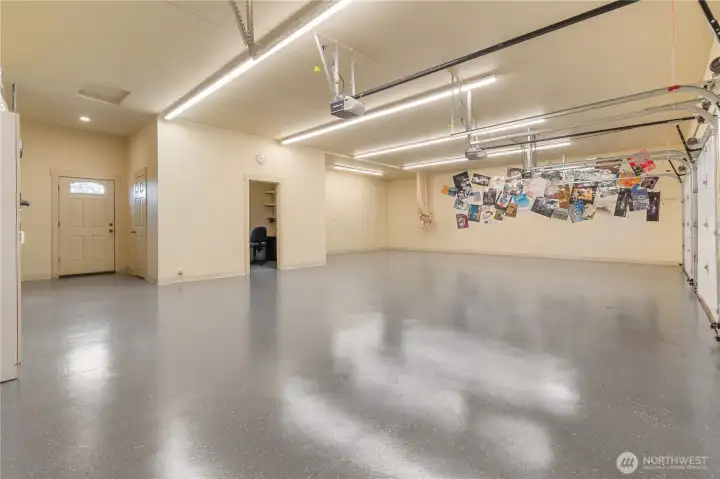 Three car garage is enormous. Doorway at center leads to small office. Two doors left are exterior door and door to half bath. All doors have electric garage door openers.