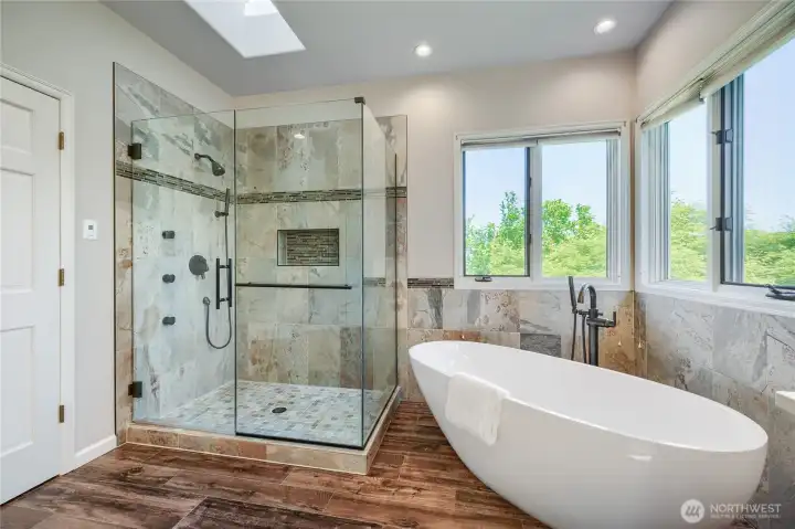 Soaking tub with glass enclosed shower with stunning views.