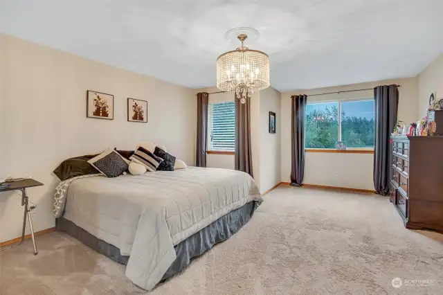 The primary bedroom is beautifully detailed with a designer chandelier .