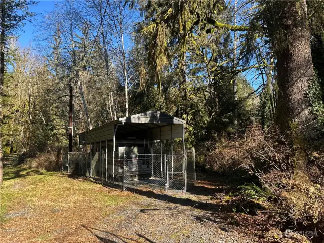 Chainlink fence surrounds motorhome & steel carport.