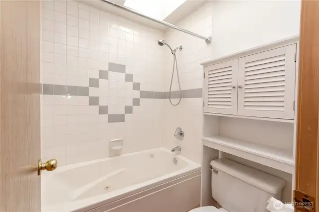 Common bathroom, stool, jetted tub and shower.