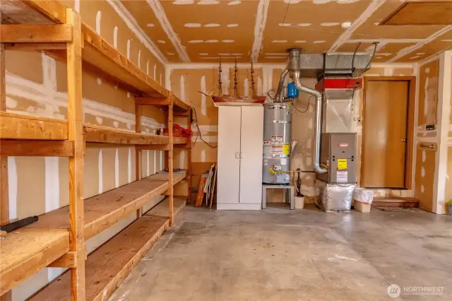 Double car garage with floor to ceiling built-in wood shelving.