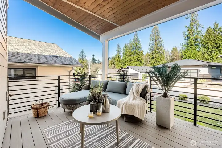 Covered outdoor living deck with natural stained wood soffits right off of the kitchen for easy access for your morning coffee, or BBQ nights. Custom metal railing, conveniently plumbed with water and electric outlets.
