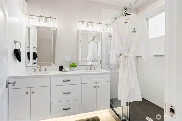 The downstairs primary bathroom features a double sink vanity, under cabinet lighting, solid one piece quartz shower, with a solid one piece quartz pan! This is a very rare feature, making the shower a seamless beauty that is easy to clean and maintain! You also have a tall linen cabinet to the left.