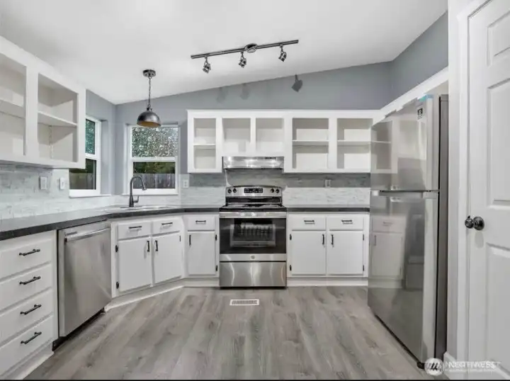 Kitchen has stainless appliances and open upper cabinets.