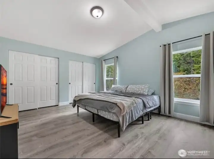 Primary bedroom at the end of the hallway for privacy, looks out to the forest beyond.