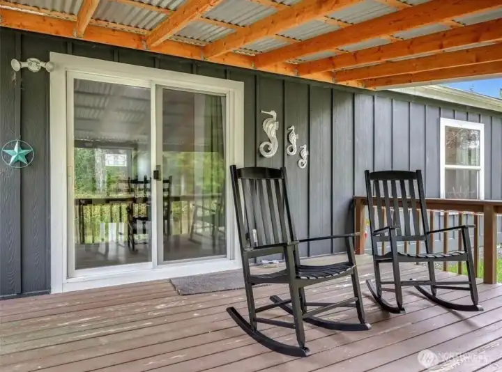 Covered back deck is a peaceful place to look out at the forest and contemplate your good life here at The Beach.