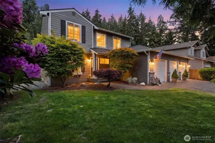 Evening exterior view showcasing the home’s landscaped front yard, covered entry, and three-car garage. Evening exterior view showcasing the home’s landscaped front yard, covered entry, and three-car garage.