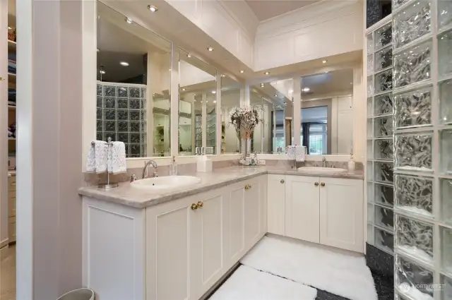 Primary bathroom features granite tile floor, massive glass block walk in shower with 8 shower heads, marble countertops with his & hers sinks, soaking tub, and vanity. Impressive millwork and great storage all throughout the primary bathroom and almost all power outlets are hidden/integrated into the cabinetry.