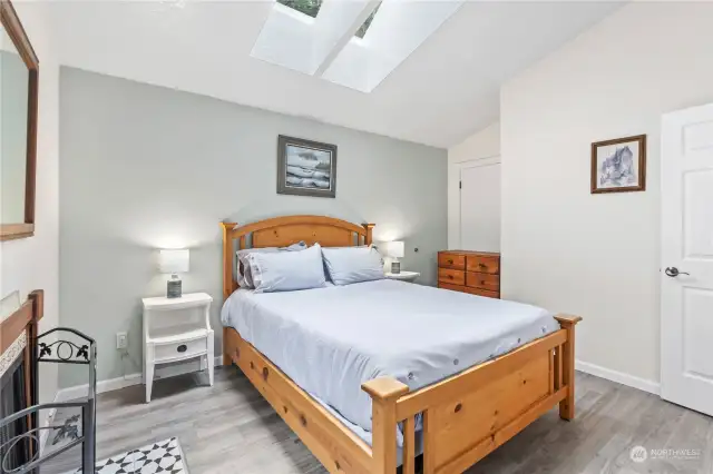 Primary Bedroom showing door (behind dresser) that accesses the Bathroom.  Notice the Skylight and Vaulted Ceilings!