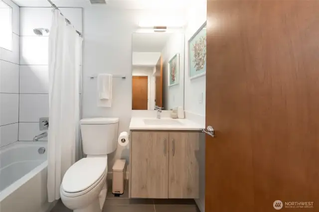 A guest bathroom featuring a tub, shower, and single vanity offers comfort and easy access for everyday use or visiting guests.