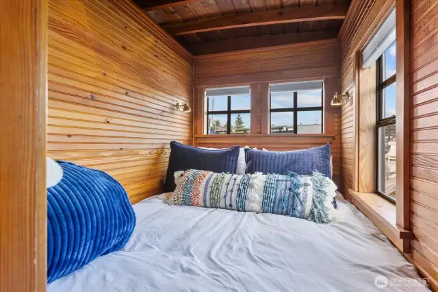 Queen bed with plenty of windows and two sweet sconces already installed.