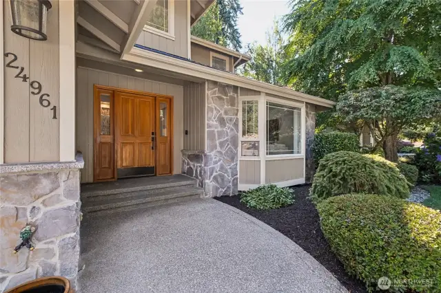 Welcoming walkway framed by lush landscaping and a charming covered porch.
