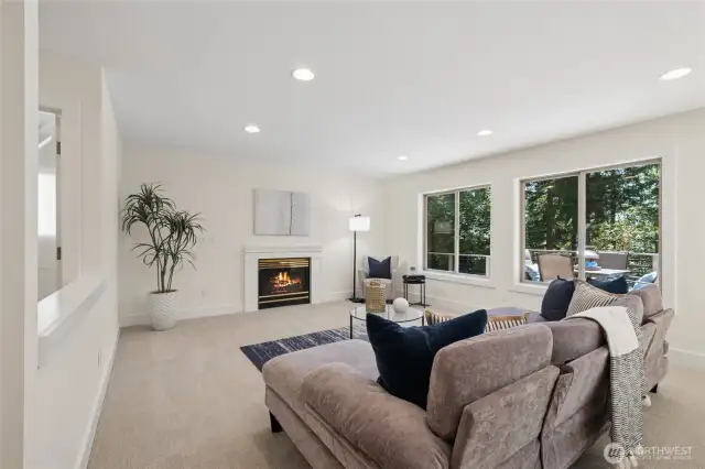 Relaxed family room filled with light, views, and a glowing gas fireplace.