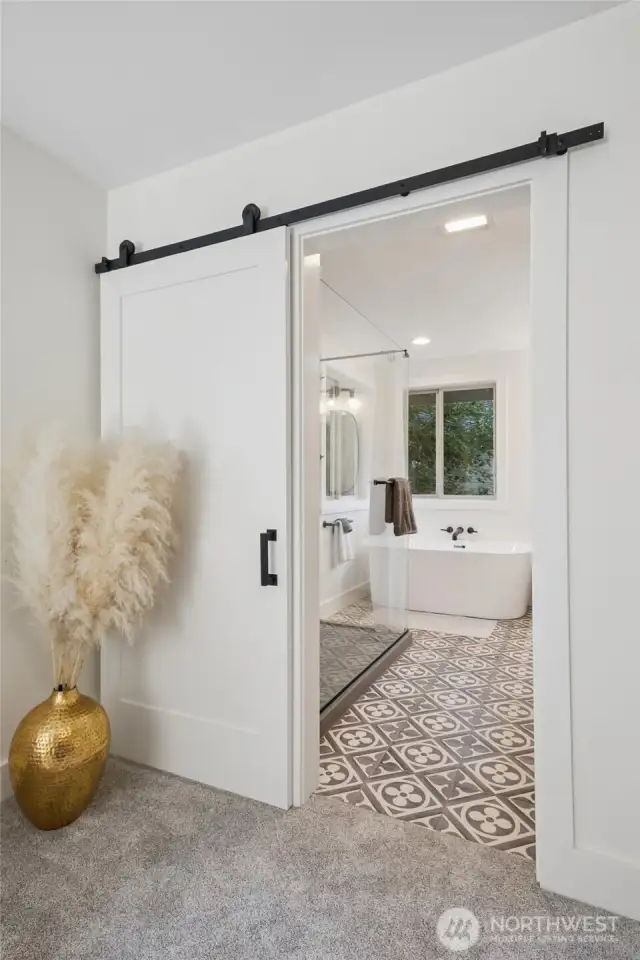 Stylish barn door opens to the spa-inspired primary ensuite bathroom.