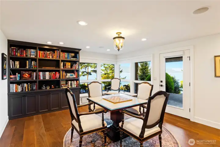 off of the media room is a richly finished library and game room with custom built-ins, water views, and access to the covered patio and hot tub.